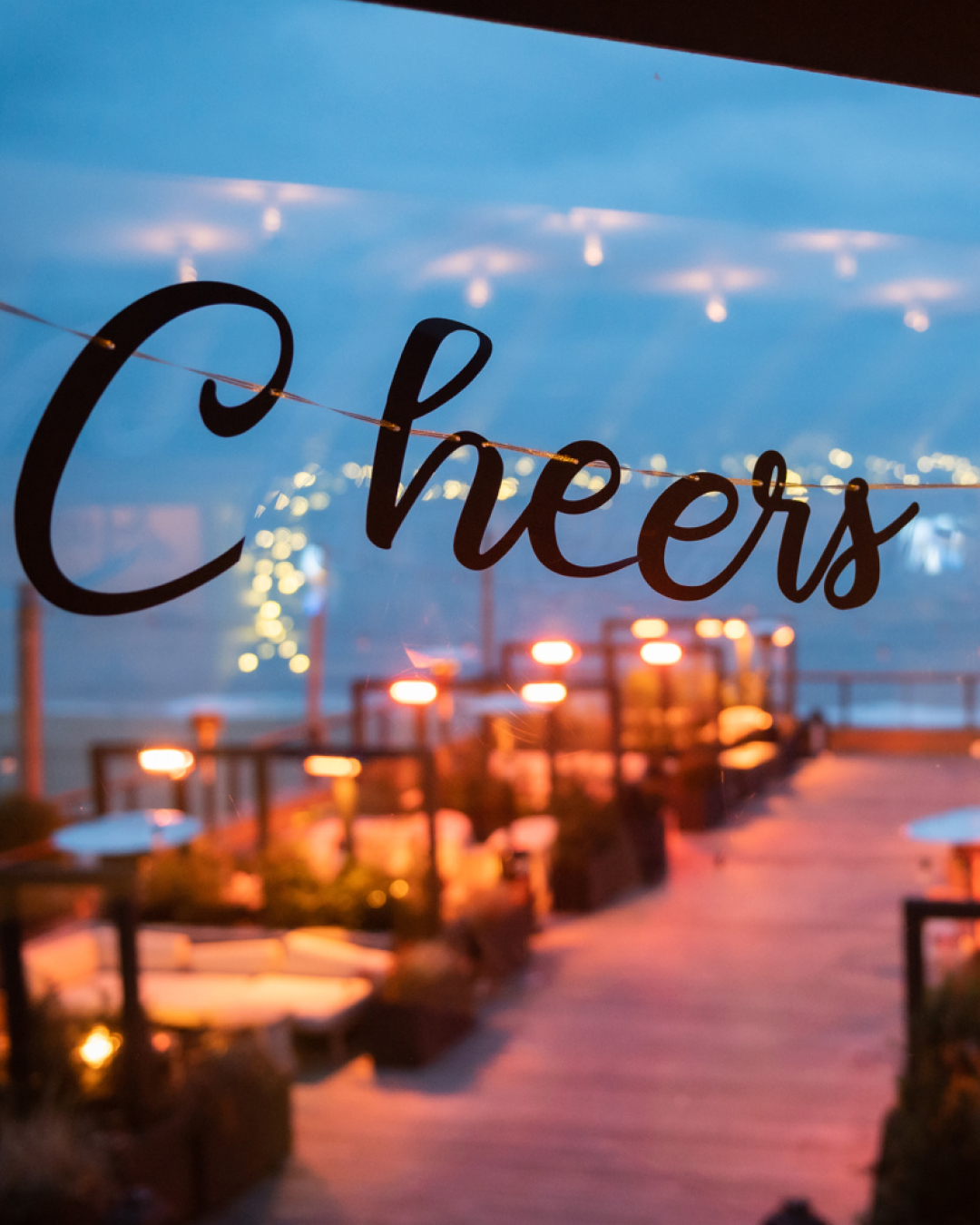 Elegant dining setting with soft lights, framed by a glass window with the text "Cheers to 2022" in cursive.